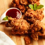 Pack GLAM Delicious crispy fried chicken served with a tangy dipping sauce on a wooden board.